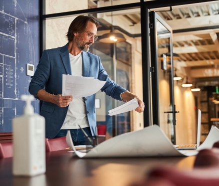 Mann mit Dokumenten in modernem Büro mit Architekturplänen.